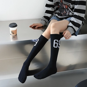 Détail de chaussettes hautes noires tricotées avec le chiffre 69 brodé sur tissu côtelé