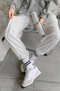 Detail view of white vertical ribbed joggers with elastic cuffs and cozy textured fabric