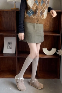 Vertical striped knee-high socks styled with vintage knit vest and green mini skirt