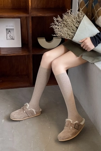 Close-up of brown suede slippers with white faux fur lining and retro metal buckle