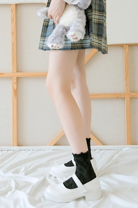 Détail de chaussettes en dentelle noire à volants avec chaussures Mary Jane blanches à plateforme