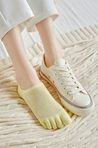 Close-up of pale yellow low-cut five-finger mesh socks worn with white canvas shoes