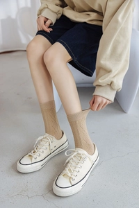 Detailed knit texture of beige argyle crew socks paired with white canvas sneakers