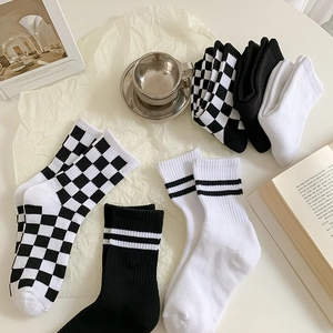 Flat lay of checkered and monochrome cotton crew socks with minimalist lifestyle props