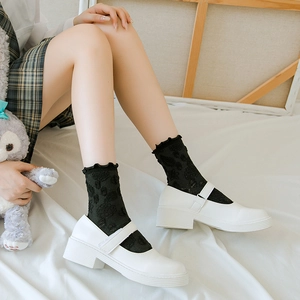 Détail de chaussettes en dentelle noire à fleurs portées avec des chaussures Mary Jane