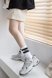 Gros plan de chaussettes blanches rayées avec lettres et baskets blanches rétro