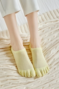 Detail of yellow cotton five-finger socks showing breathable mesh and split-toe design