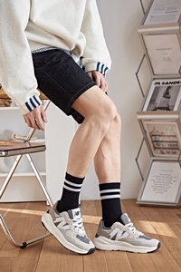 Gros plan sur des chaussettes rayées noir et blanc portées avec des baskets grises