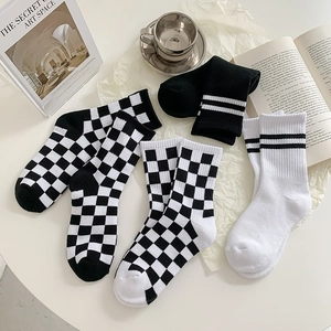 Flat lay of checkered and striped mid-calf socks with lifestyle props in a minimalist setting