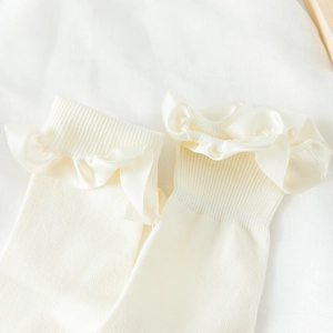 Close-up of creamy white JK socks with elegant satin ruffle lace trim detail