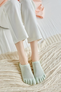 Breathable mesh knit five-finger socks in mint green color shown on a knit blanket