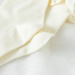 Macro detail of cream knit fabric texture with a silky satin bow decoration