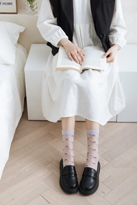 Detail of light purple mesh socks with dark purple bow patterns and black loafers