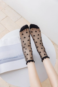 Close-up of sheer black mesh crew socks with heart patterns and ruffle trim edges