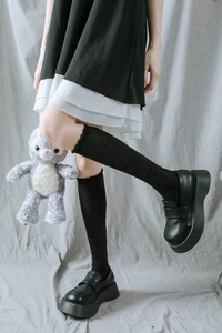 Détail de chaussettes hautes JK noires avec motif cœur et bords à volants et mocassins