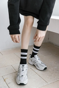 Détail de chaussettes blanches à rayures portées avec des baskets rétro argentées