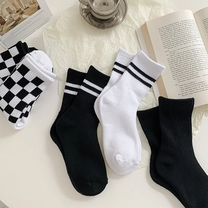 Flat lay of checkered and striped cotton crew socks with ribbed cuffs on white paper