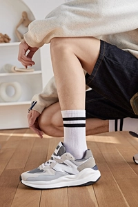 Gros plan de chaussettes rayées rétro portées avec des baskets grises sur parquet