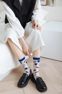 Detail of sheer mesh socks with blue heart patterns and LOVE text worn with loafers