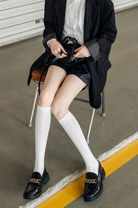 Detail of white diamond pattern knee-high socks paired with chunky gold chain loafers