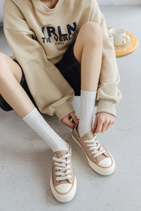 Detail of white argyle knit mid-calf socks paired with classic khaki canvas shoes