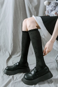 Détail de chaussettes hautes noires avec motif de cœur et bordure en dentelle