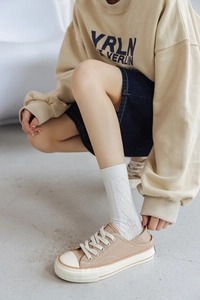 Close-up of khaki canvas shoes with white rubber soles paired with white cotton socks