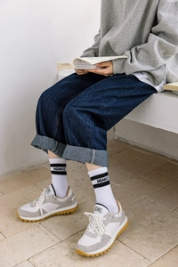 Gros plan de chaussettes blanches lettrées avec baskets grises et jean bleu