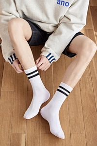 Gros plan de chaussettes de sport blanches en coton avec rayures sur sol en bois