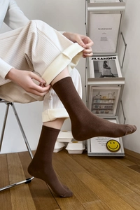 Detail of dark brown cotton mid-calf socks with ribbed cuffs shown on model for warmth