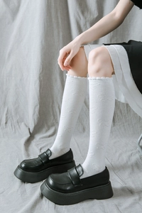 Détail de chaussettes JK blanches avec motifs papillons et dentelle aux chevilles
