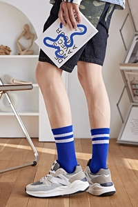 Détail de chaussettes mi-hautes bleu marine à rayures blanches et texture côtelée
