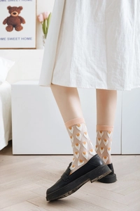 Detail of sheer glass silk socks with orange hearts and cream ribbed cuffs for women