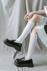 Détail de chaussettes JK blanches avec broderie papillon et bord ondulé