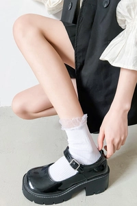 Detail of white ruffle lace trim socks paired with black shiny patent leather Mary Janes