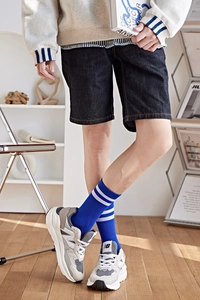 Gros plan de chaussettes de sport bleues à rayures avec baskets rétro sur parquet