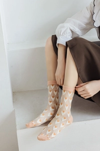 Detail shot of sheer mesh socks with orange and white heart patterns for women
