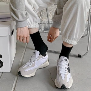 Mid-calf checkerboard socks worn with retro grey and white sneakers in a street style
