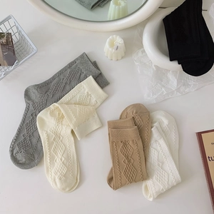 Detail of argyle pattern knit socks in grey and cream with ribbed cuffs and soft texture