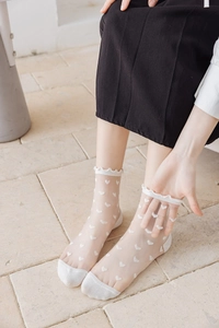 Detail of sheer glass silk socks with heart jacquard patterns and delicate ruffle cuffs
