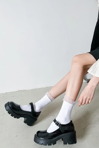 Detail of white mid-calf socks with mesh lace trim paired with black Mary Jane shoes
