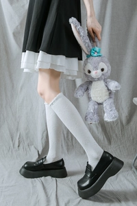 Détail de chaussettes hautes blanches JK avec motifs papillon, dentelle et mocassins