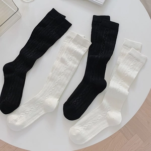 Close-up of black and white knit knee-high socks with diamond and cable textures