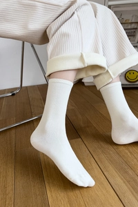 Detail of white ribbed cotton mid-calf socks showing elastic knit texture on legs