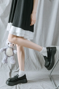 Détail de chaussettes hautes blanches à volants avec mocassins noirs à plateforme Lolita
