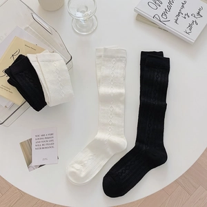 Close-up of black and cream knee-high socks with knitted diamond texture patterns