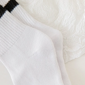 Détail de chaussettes de sport en coton blanc à rayures noires avec texture au talon