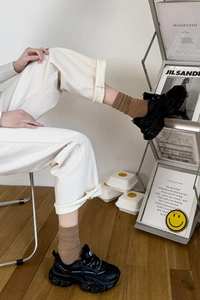 Detailed view of women's brown mid-calf socks with black chunky sneakers and corduroy pants
