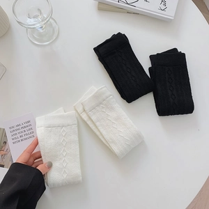 Detail view of knee-high knit socks in black and white with diamond cable texture
