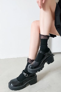 Detail of black platform Mary Jane shoes in patent leather with lace trim crew socks